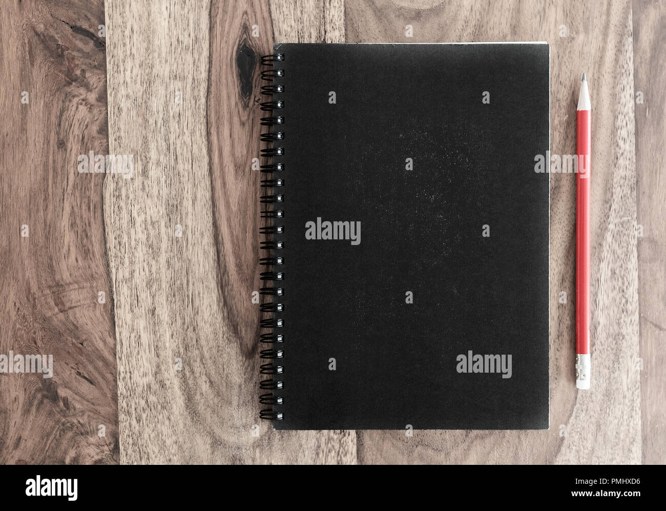 closed black spiral notebook and pencil on wooden desk Stock Photo