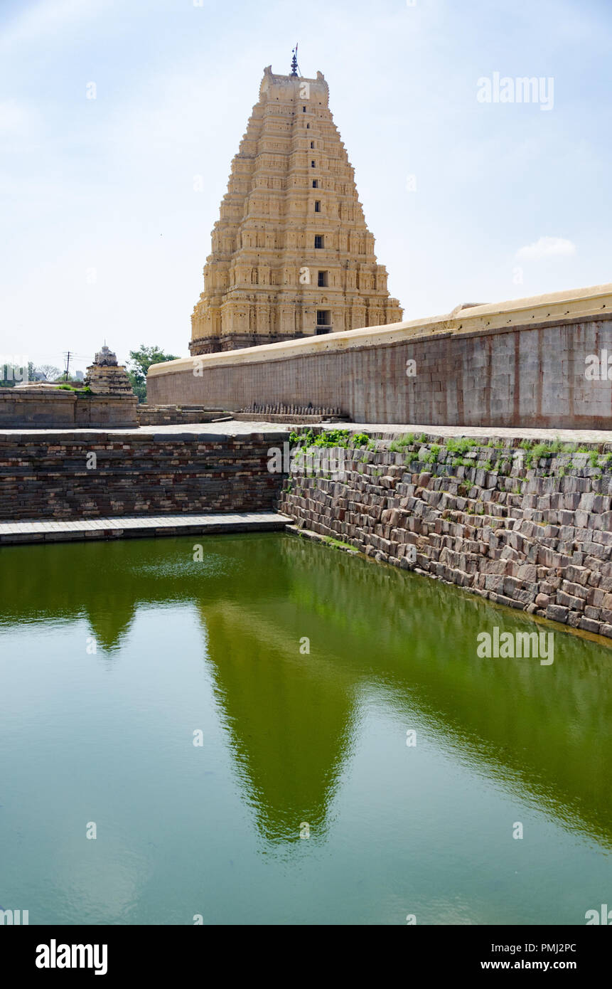 The nine-tiered eastern gateway ( gopuram ) and its reflection in the pushkarani ( temple tank ) at Virupaksha Temple, Hampi, Karnataka, India Stock Photo