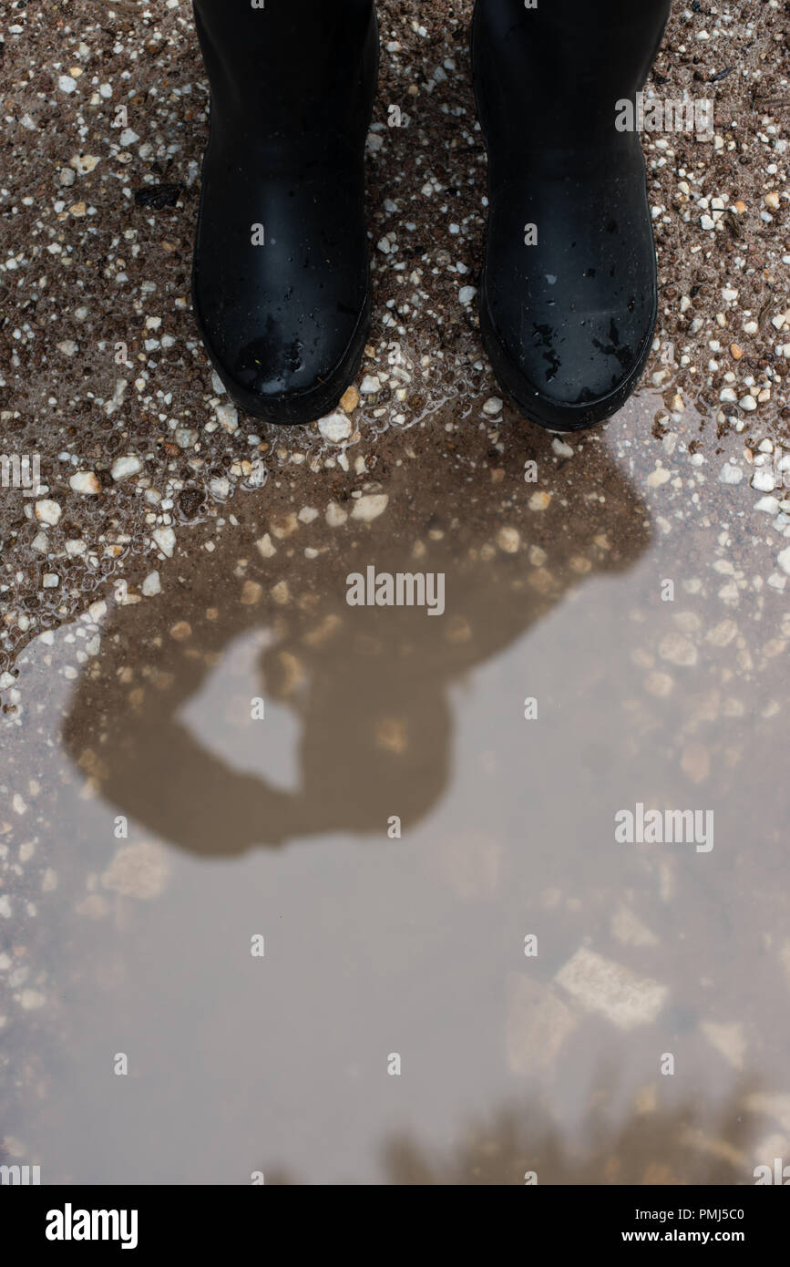 Woman standing by a puddle wearing wellington boots Stock Photo