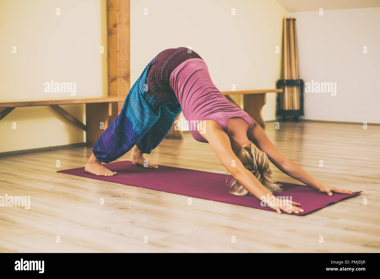 Woman doing yoga Adho Mukha Svanasana/Downward facing dog pose.Toned image. Stock Photo