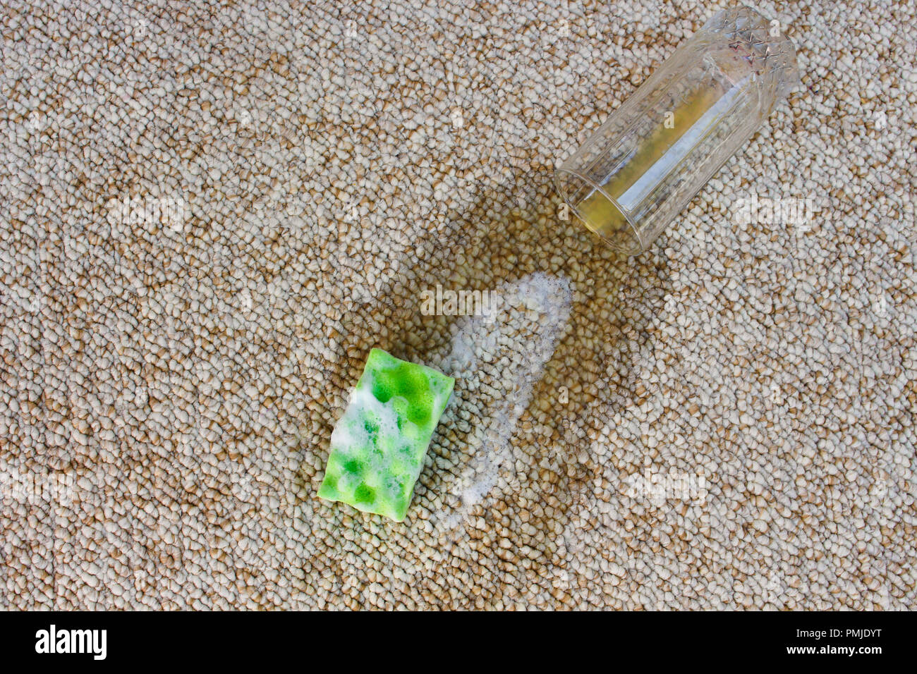 Glass of orange juice fell on carpet. Drink spilled on floor. Sponge