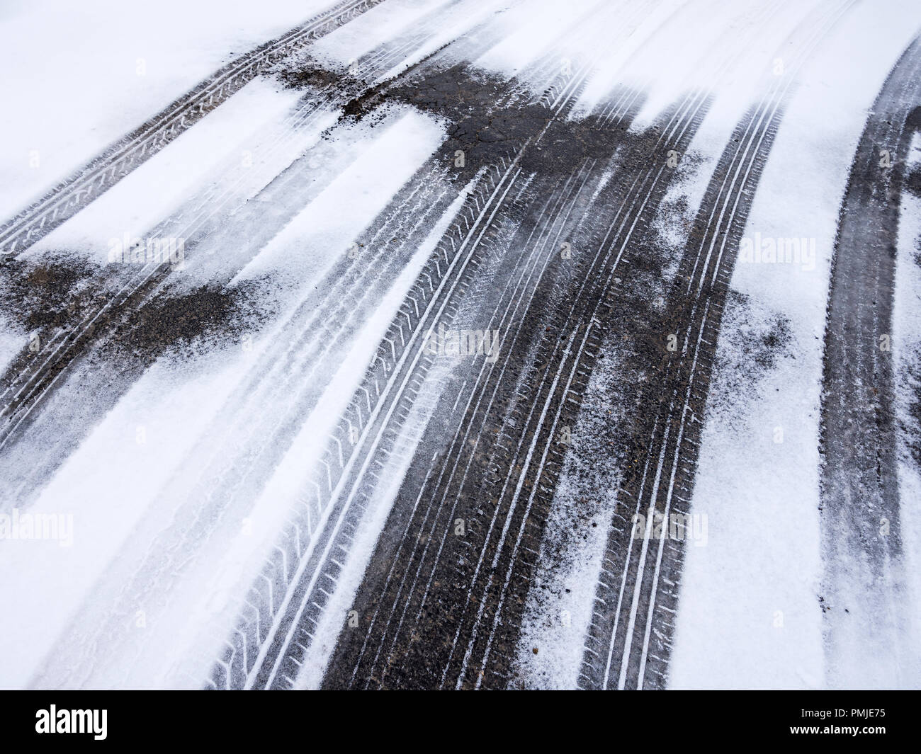 Tyre tracks on road covered in light snow - France. Stock Photo