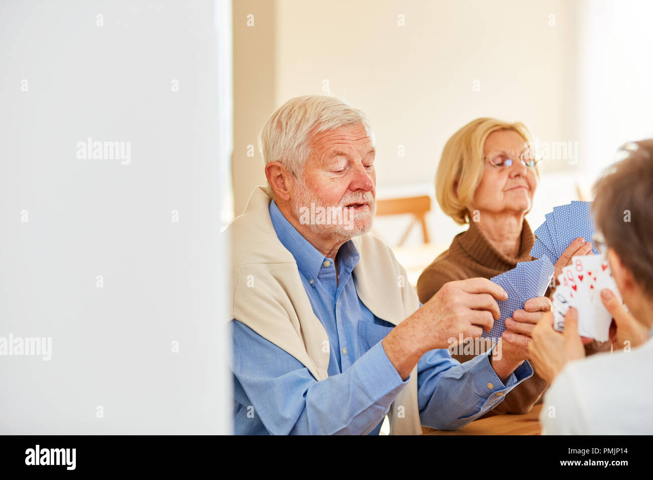 Group of seniors playing card games together in a retirement home or at home Stock Photo