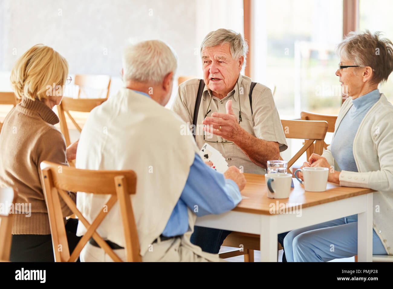 Group of seniors as friends and pensioners playing cards in retirement home Stock Photo