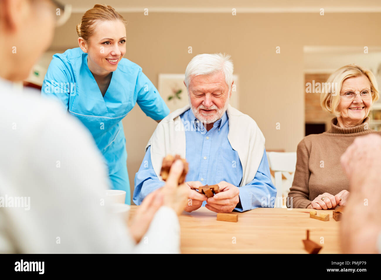 Nursing home care for seniors group with dementia in the puzzle game with wooden puzzle Stock Photo