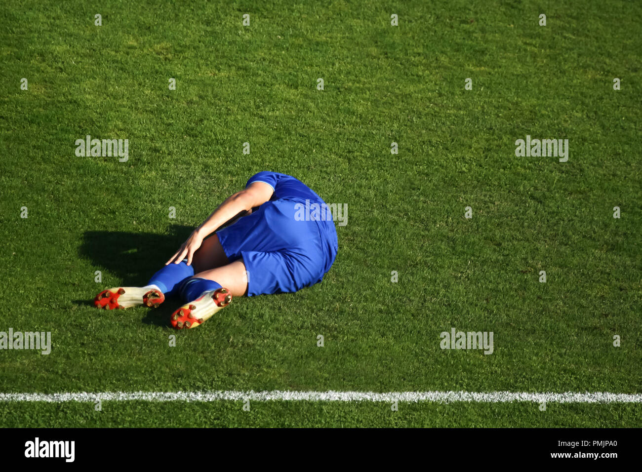 An injured football player laying down on the grass floor in pain and