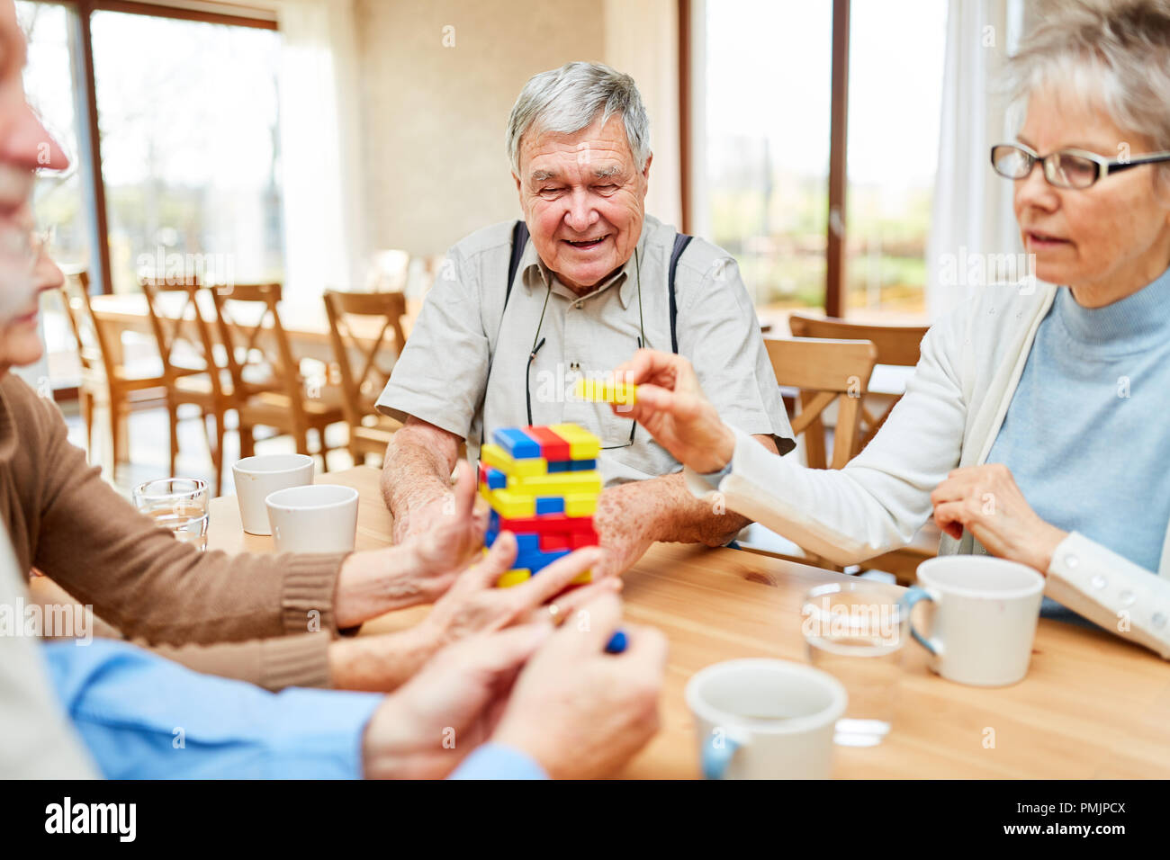 Seniors with dementia stack together colorful building blocks as a