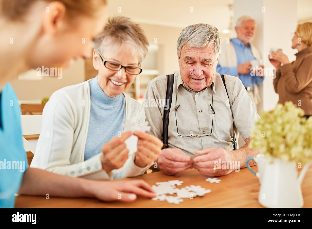 Seniors with Alzheimer's disease or dementia playing puzzle with senior care Stock Photo