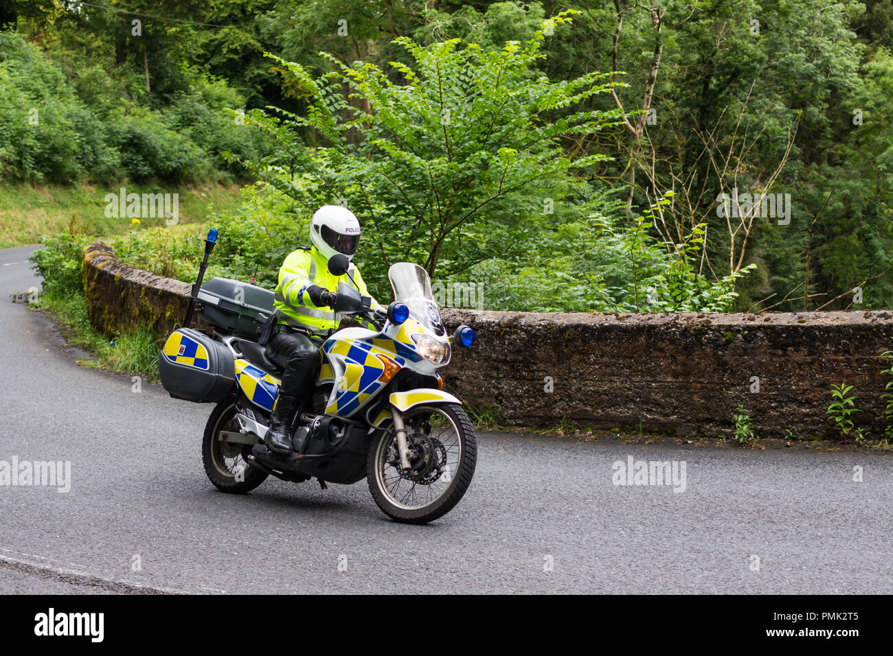 Police motorbike outrider rounding a bend, Glenarriff, County Antrim, N.Ireland. Stock Photo