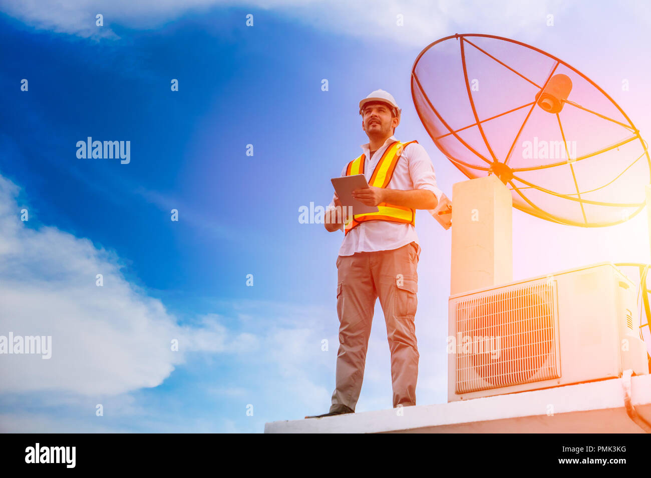 home worker handyman fix air chiller and satellite dish stand for future blue sky background Stock Photo