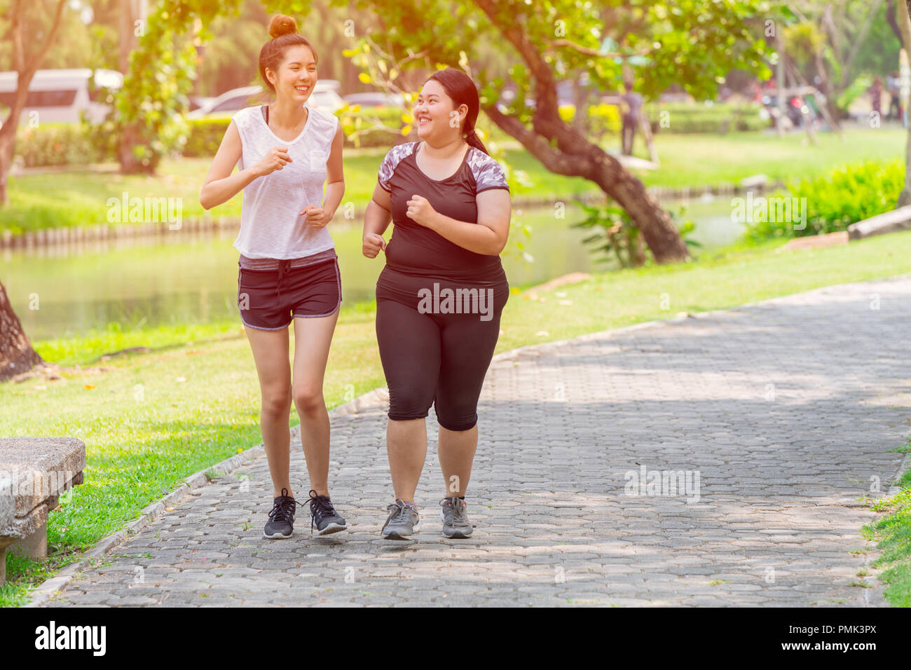 Asian two thin and fat girls friend running jogging park outdoor in the morning Stock Photo