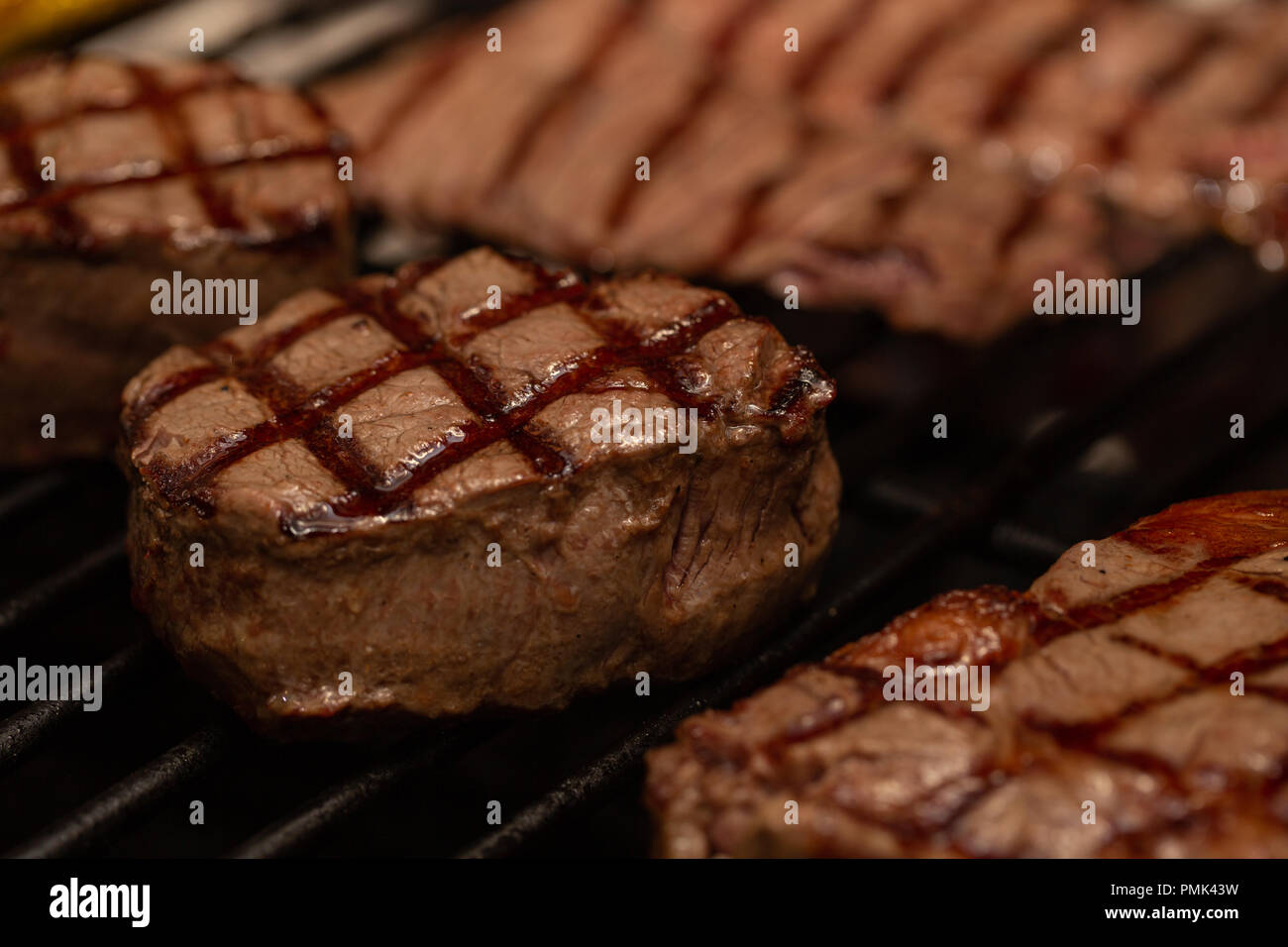 Three grilled beef tenderloin steaks coated bacon on grill. Macro