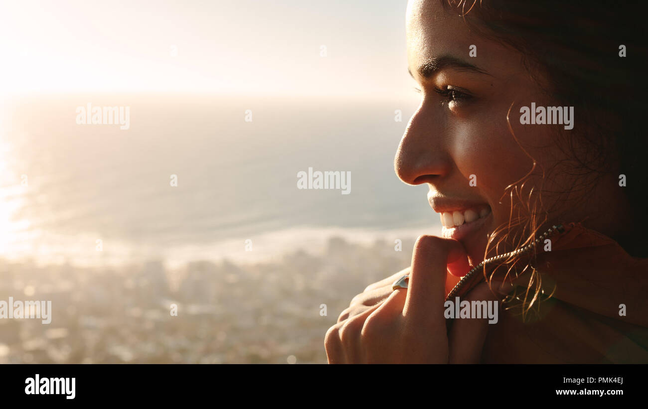 Close up of african female face. Woman standing outdoors and looking at the view with smile on her face. Stock Photo