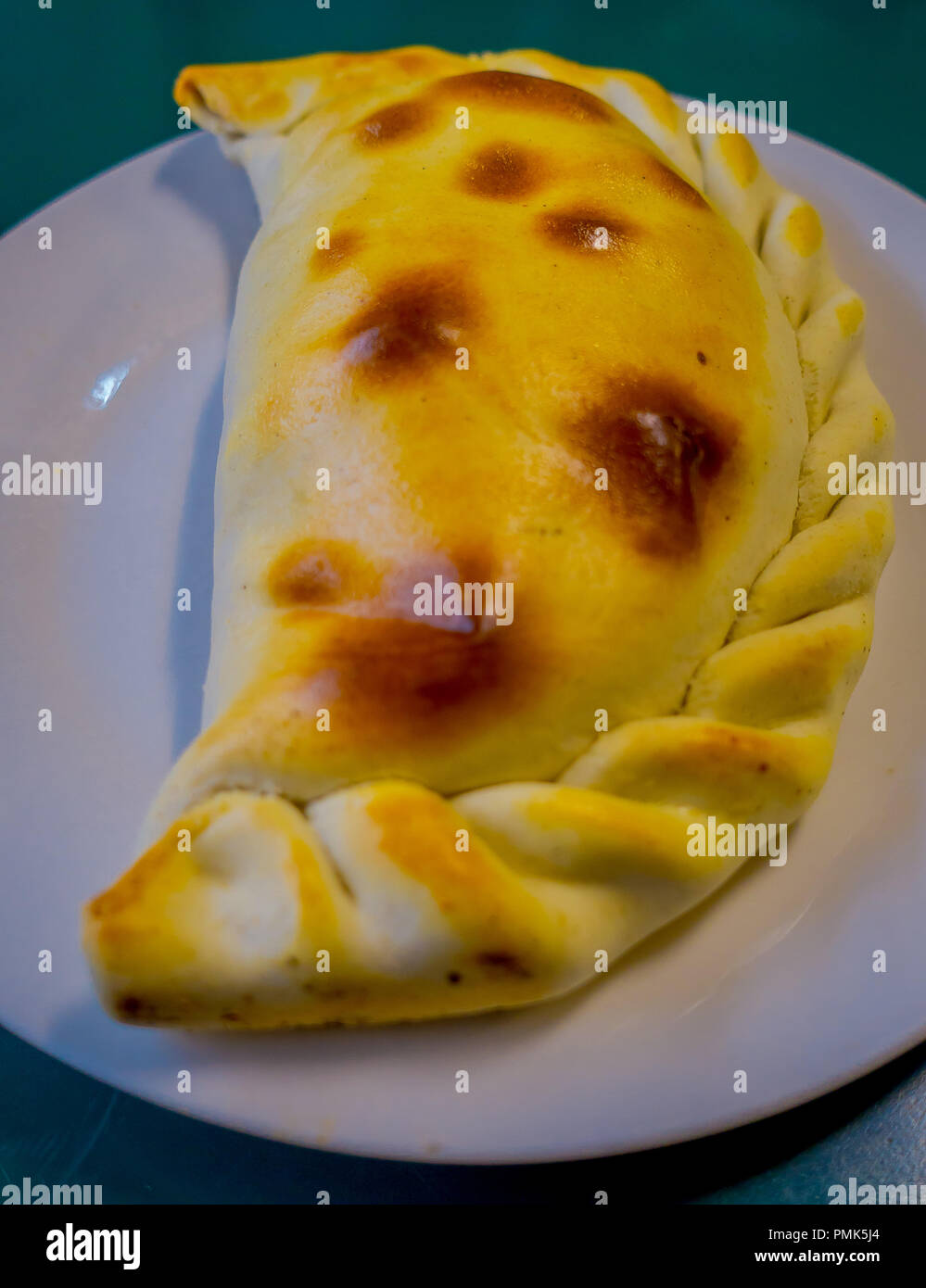 Chilean Empanadas, baked pastry stuffed with ham and cheese, photographed with natural light over a white plate Stock Photo