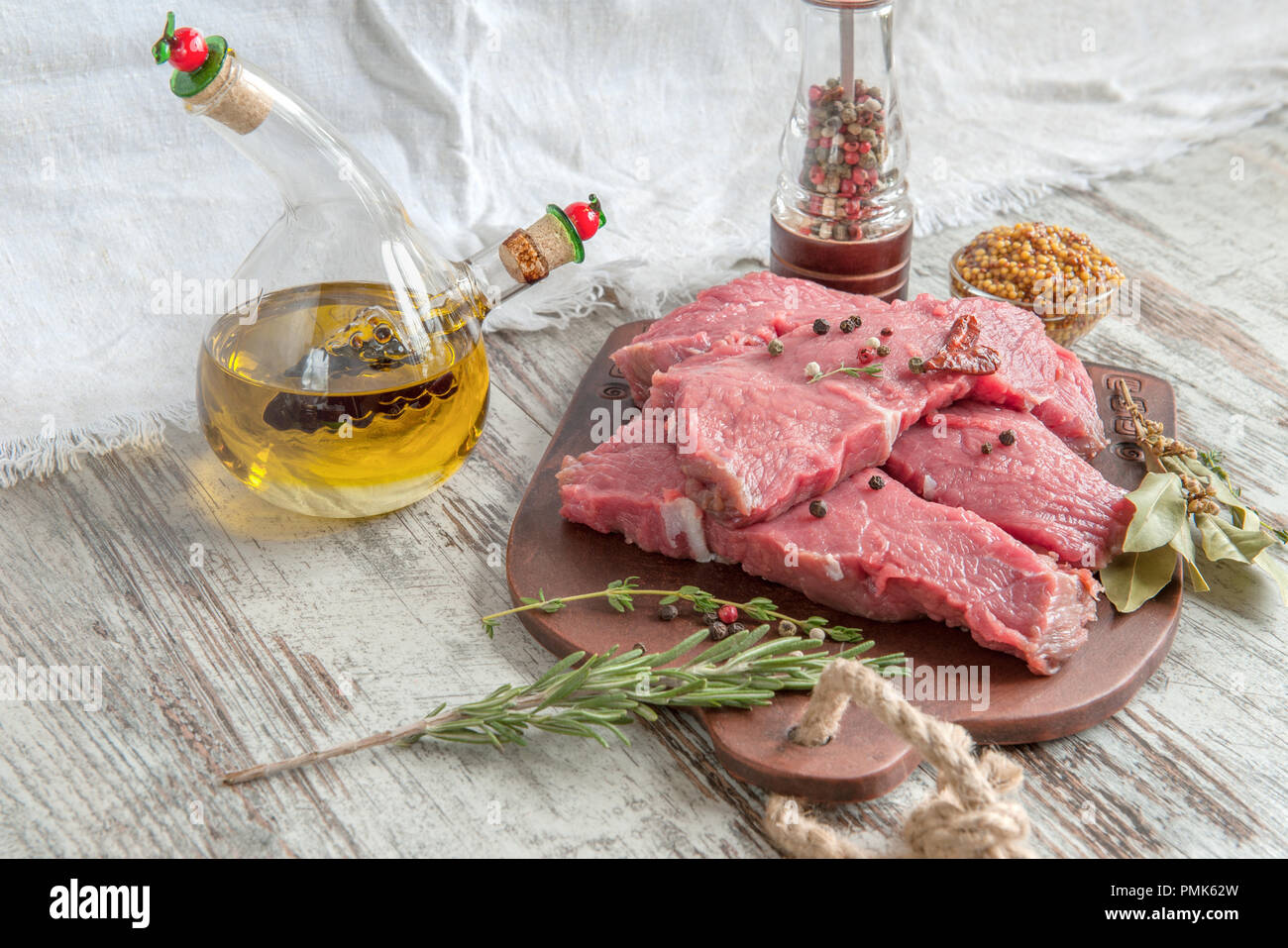 Raw meat pieces on wooden cutting board with oil, spices, marinade