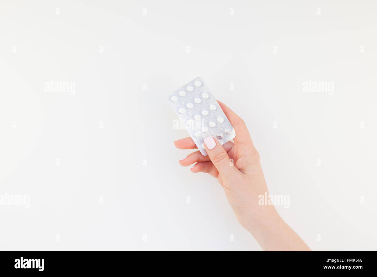 woman hand with pastel manicure polish holding pills in blister