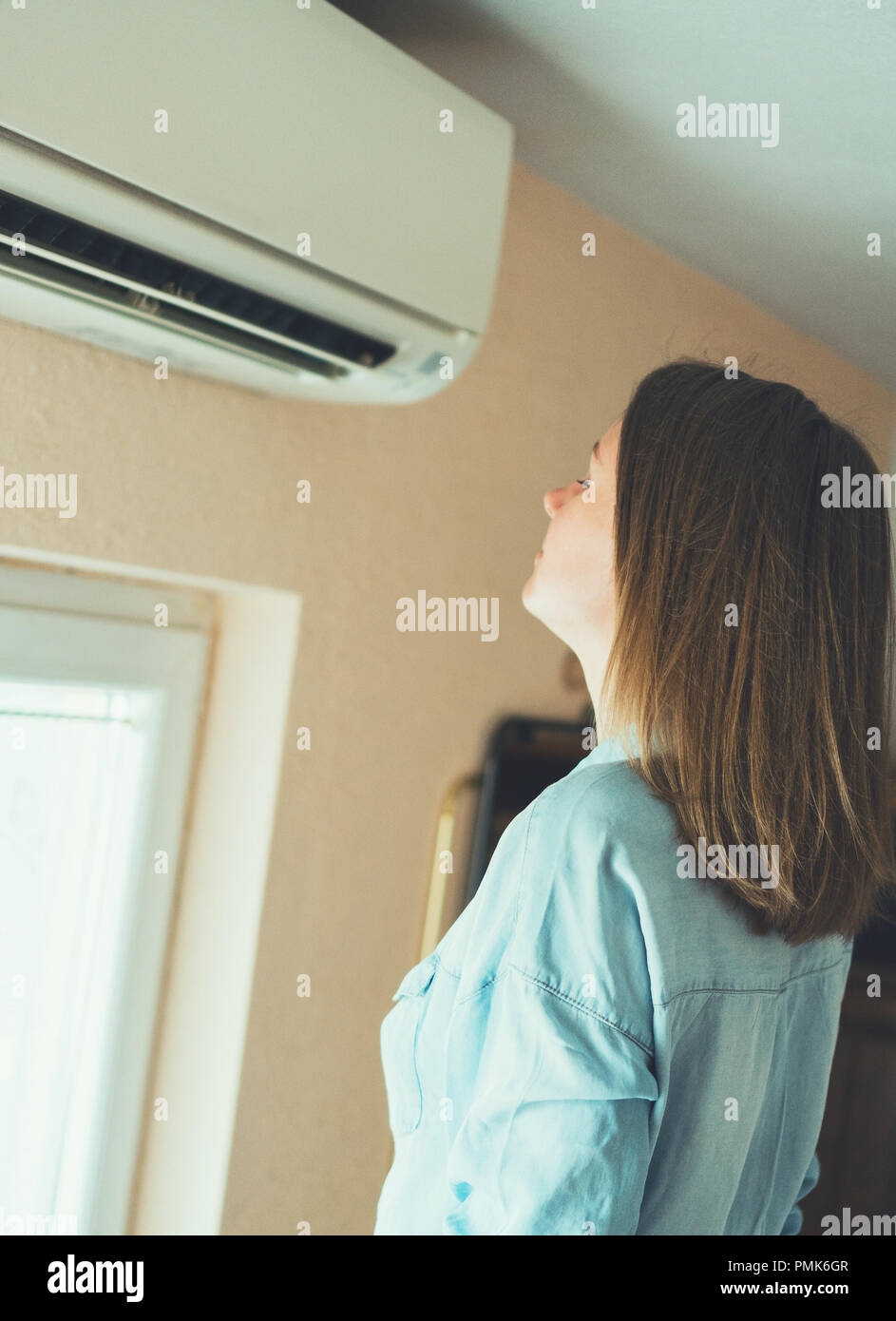 Women dying from the heat standing in front of the air conditioner