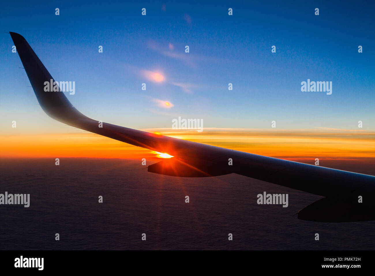 Blue planet Earth sky seen from high above through an airplane window. Unique panoramic high altitude aerial view of a flaring tropical sunset in the  Stock Photo
