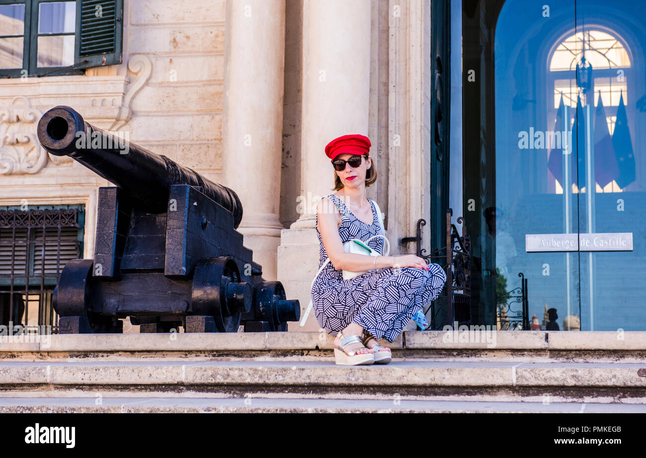 Woman, wearing red hat and red lipstick, posing beside cannon, Valletta, Malta, Europe Stock Photo