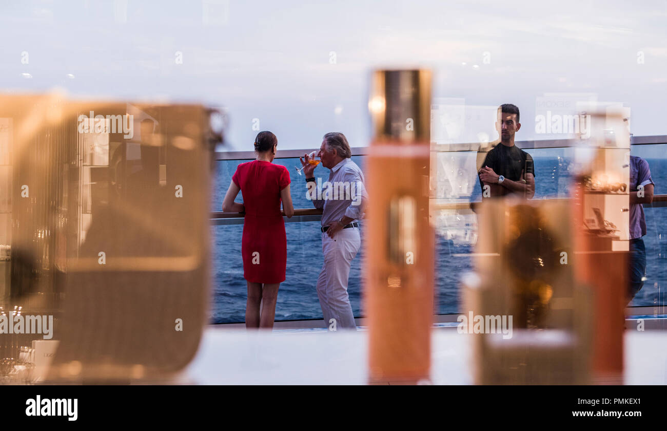 Passengers drinking and relaxing on deck of cruise ship MSC Seaview, reflections in view, focus on background Stock Photo