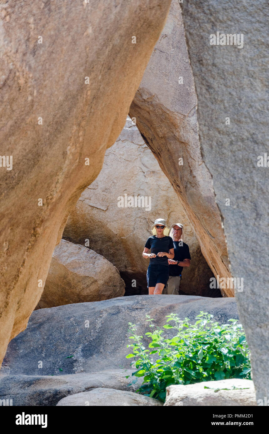 Huge boulders form a natural frame around a curious couple at Hampi, Karnataka, India. Stock Photo