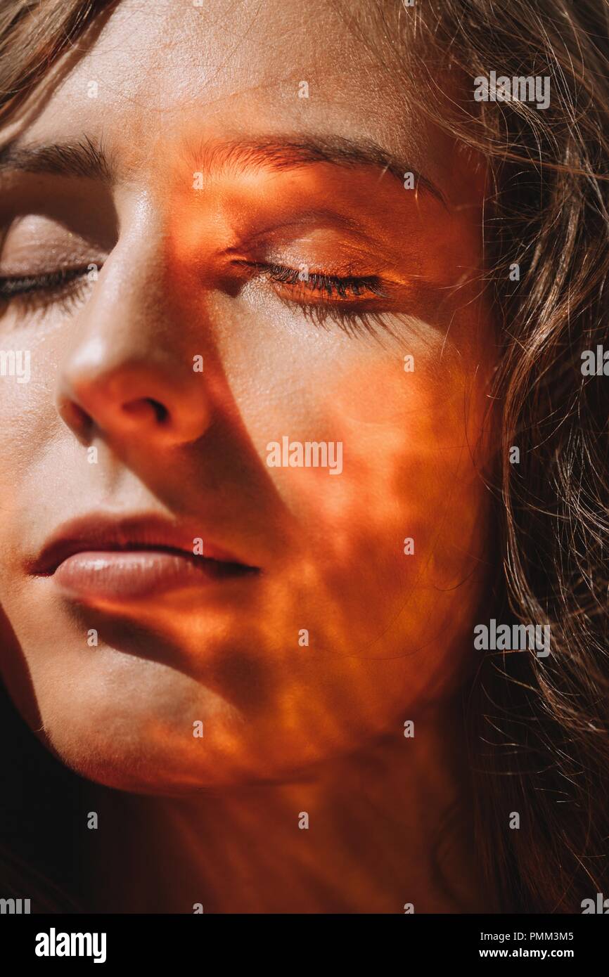 Close-up portrait of a woman with light reflecting on her face Stock Photo