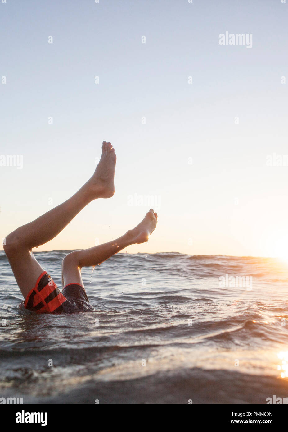 Boy's legs sticking out of the ocean, Orange County, United States