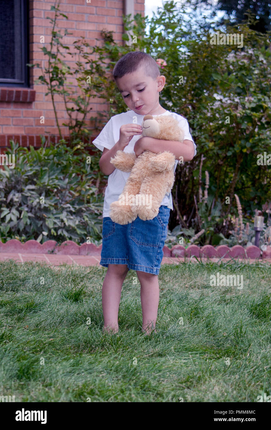 A boy plays with his favorite stuffed friend, his bear Stock Photo