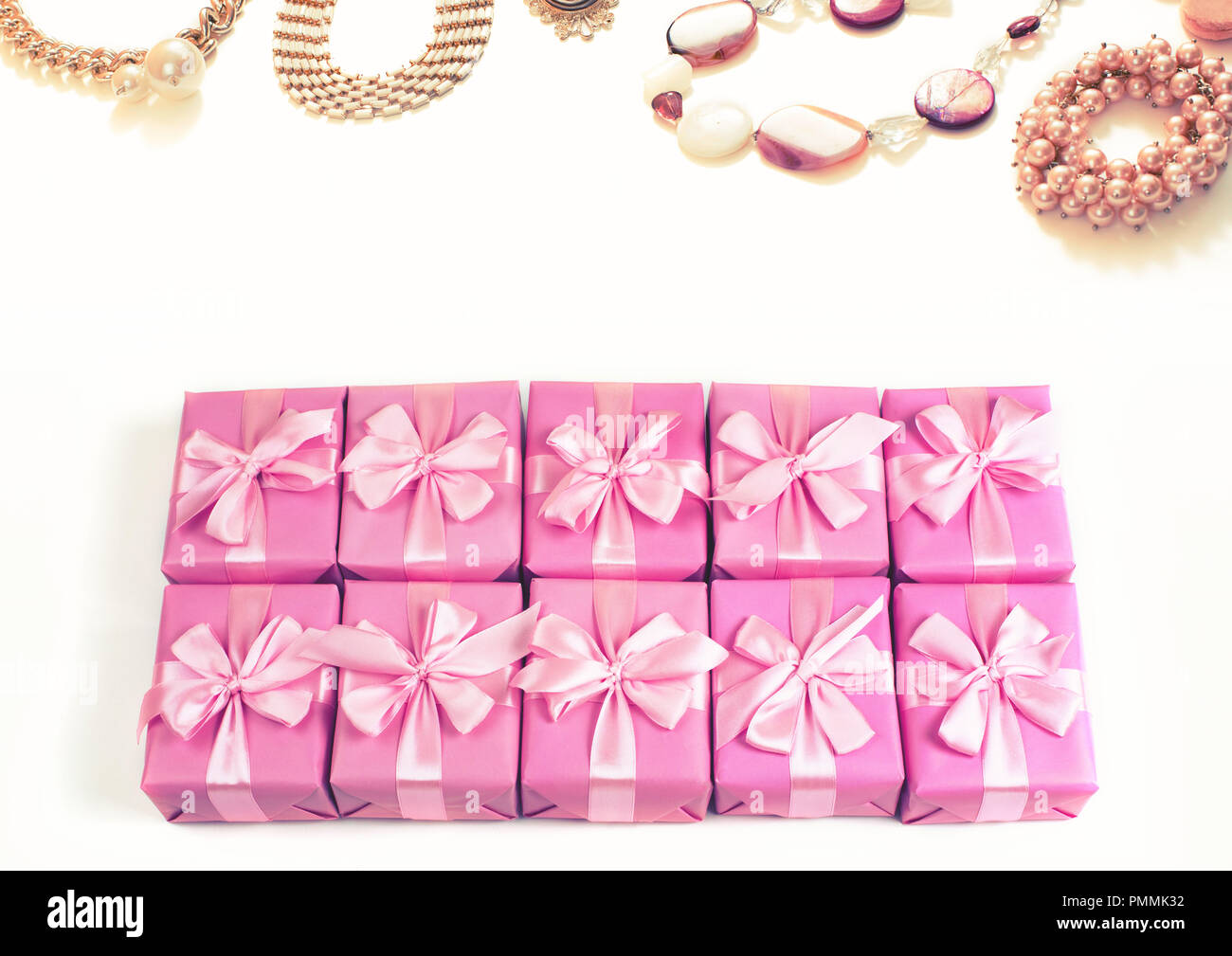 Rows of boxes with gifts decoration ribbon satin bow pink fashion accessories for women jewelry pearl necklace bracelet. A top view of Flat lay toning Stock Photo