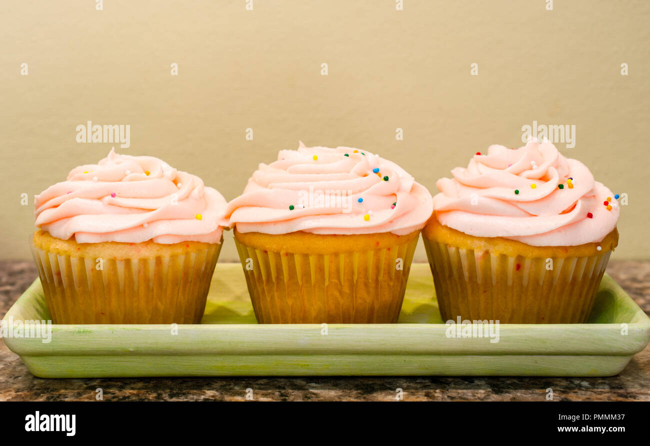 Swirls of pink butter cream frosting top homemade cup cakes. Delicious sweet treat for celebration or party or tasty snack. Stock Photo