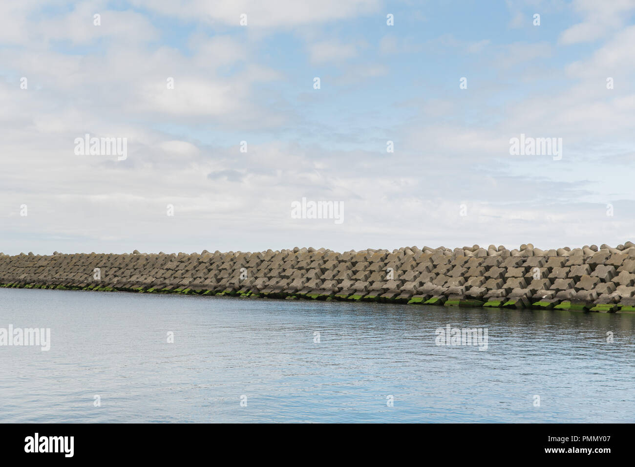 Manmade sea wall / defence / barrier built with blocks of cross-shaped concrete Stock Photo