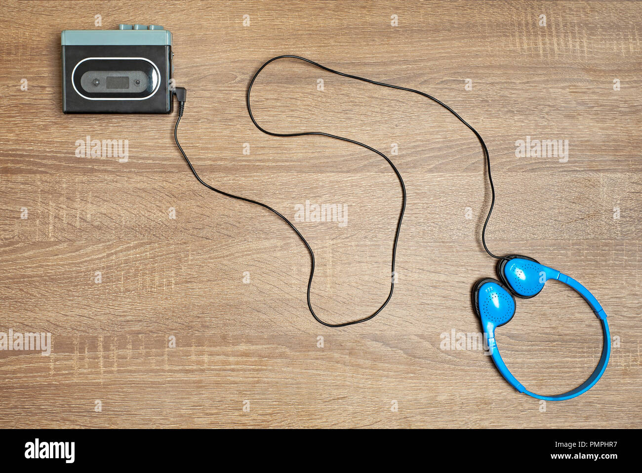 Retro walkman and blue headphones on the wooden brown background. Stock Photo