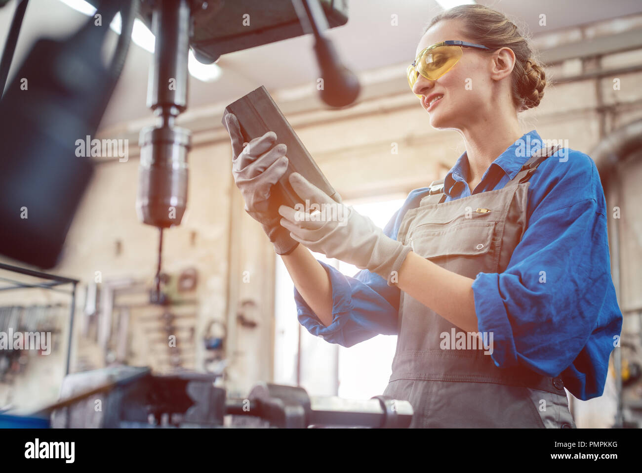 Woman in metal workshop checking workpiece Stock Photo