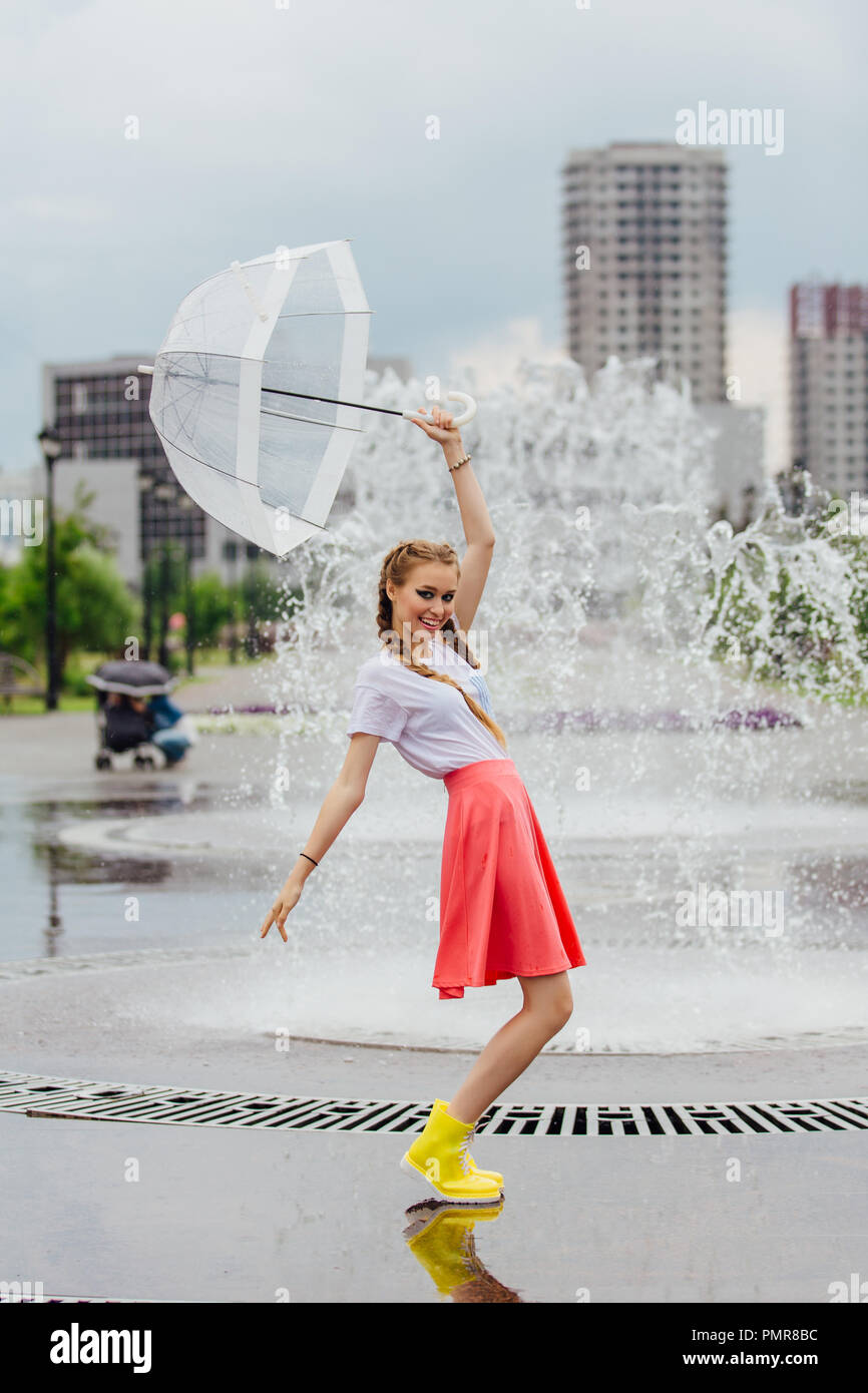 Young pretty girl with two braids in yellow boots and with transparent