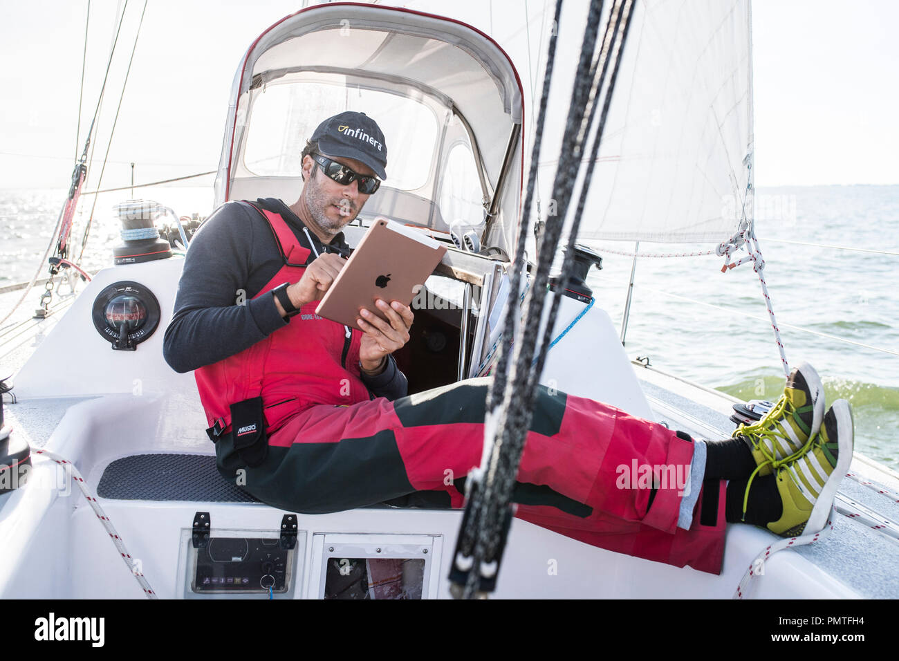 Sailor looking on an ipad while sailing. For navigation and weather. Stock Photo