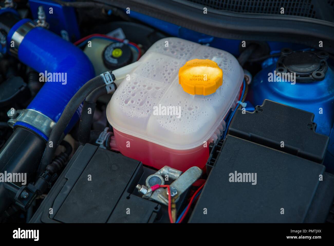 Plastic cooling liquid tank in car engine. Antifreeze radiator liquid