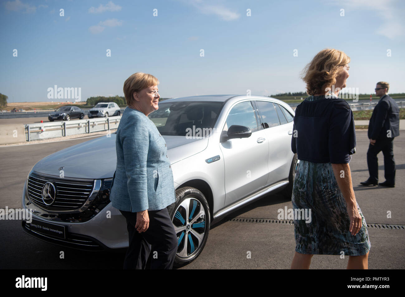 19 September 2018, Baden-Wuerttemberg, Immendingen: German Chancellor Angela Merkel (l, CUD) passes a Mercedes-Benz EQC 400 4MATIC during the commissioning of a new testing and technology center of Daimler AG, and a Daimler AG employee passes by. Photo: Marijan Murat/dpa Credit: dpa picture alliance/Alamy Live News Stock Photo