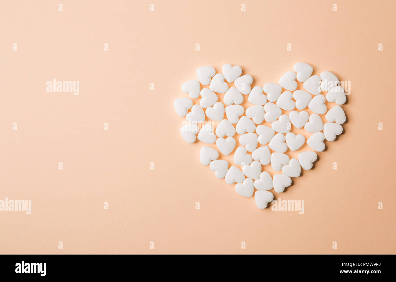 Heart shaped pills on a beige background. Stock Photo
