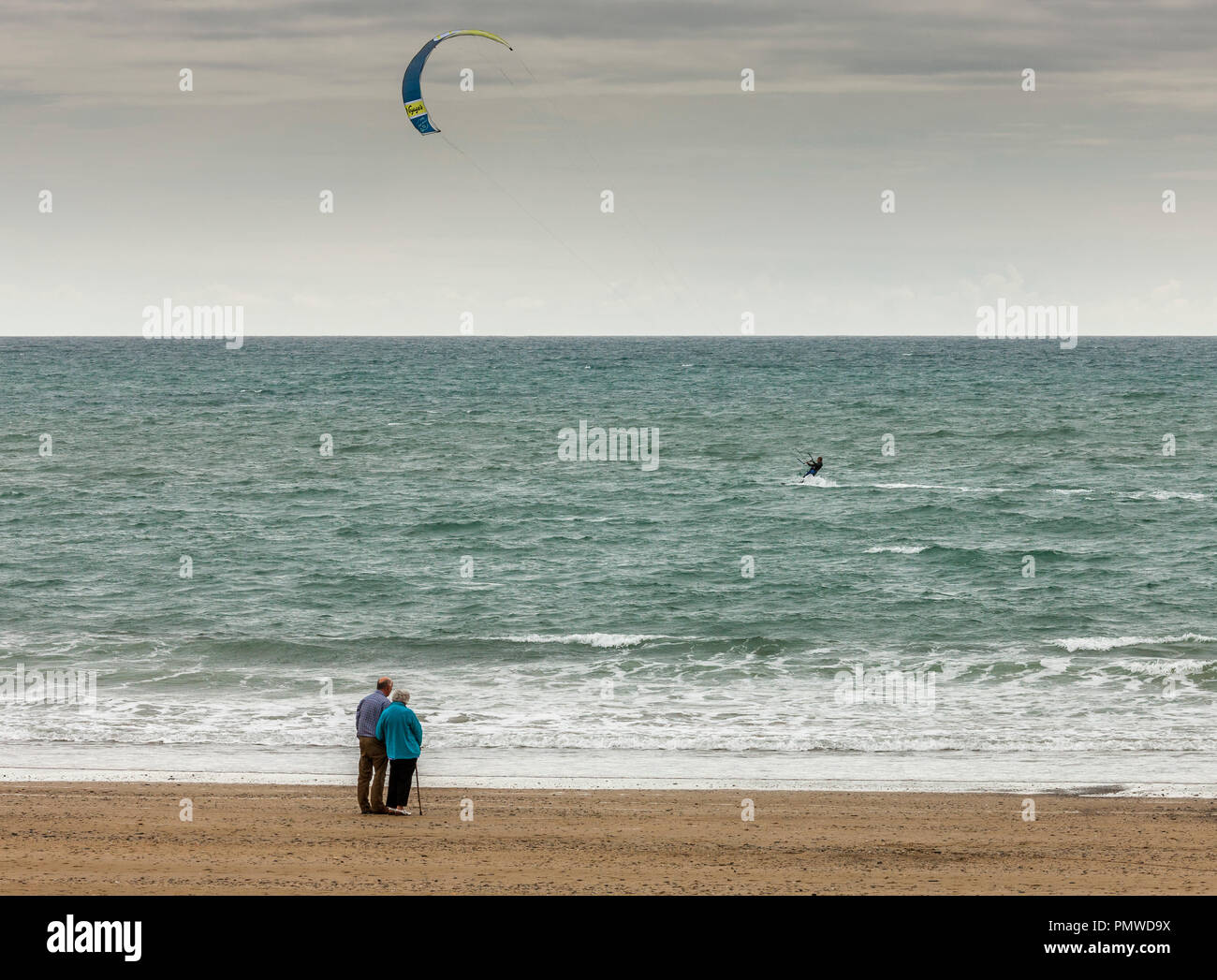 Garrettstown, Cork, Ireland. 29th July, 2017. An elderly couple watch a man windsurfing while out for a walk on the beach  at Garrettstown strand Co.  Stock Photo