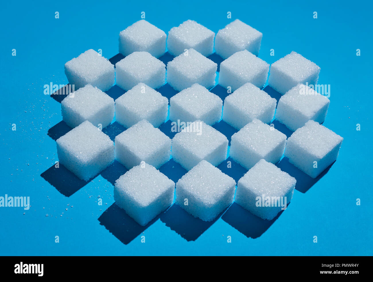 Sugar cubes forming checkered pattern on blue background Stock Photo