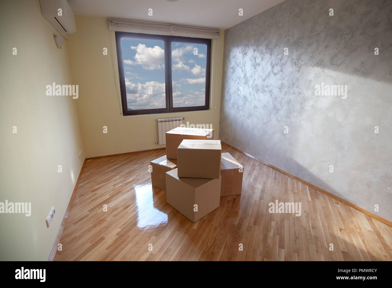 Renewed room with painted walls, varnished lacquered parquet and several carton boxes in the middle. Stock Photo
