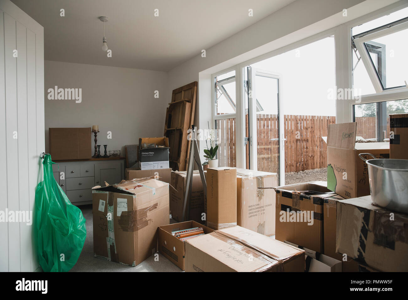 Dining room is full of furniture and cardboard boxes as a family are moving in. Stock Photo
