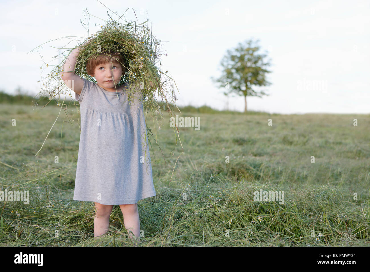 Cute girl playing with grass in rural field Stock Photo - Alamy