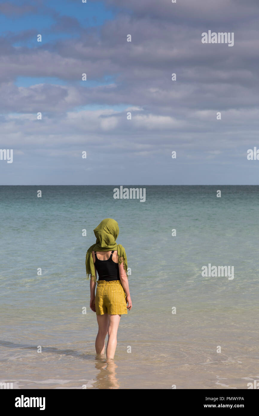 Serene woman with headscarf wading in sunny ocean Stock Photo