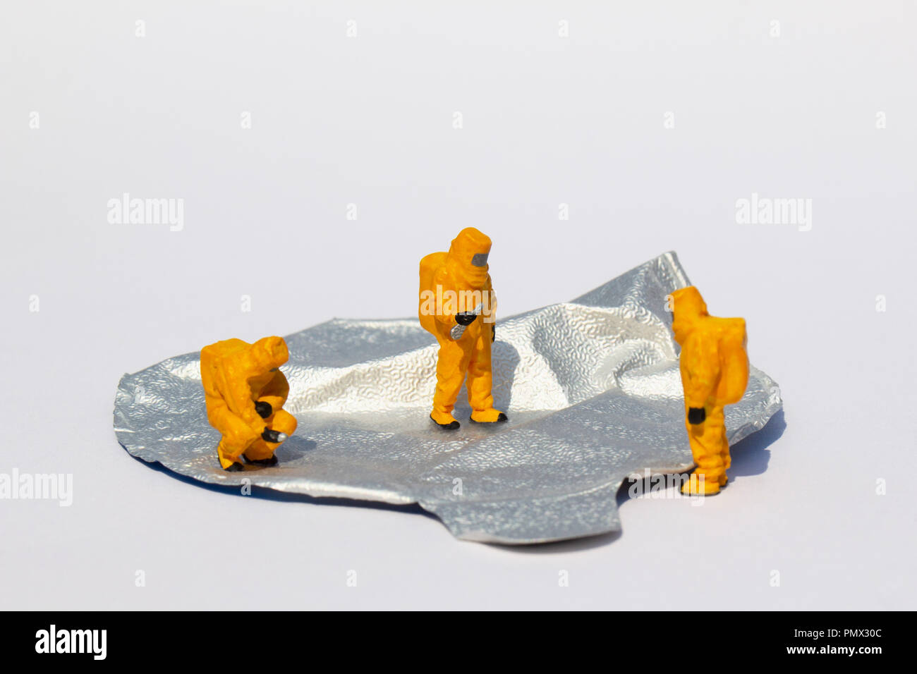 Small scientists in clean suits examining foil yogurt lid Stock Photo