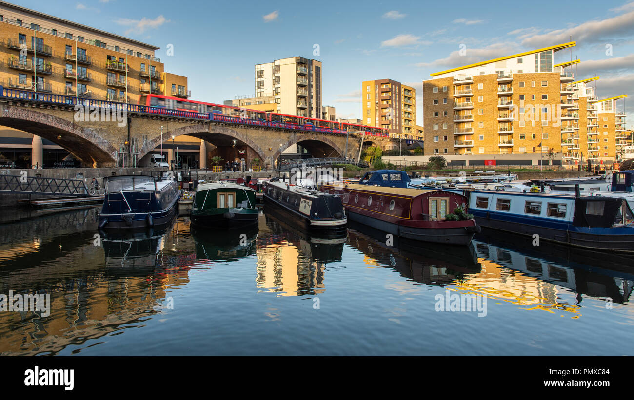 London, England, UK - September 14, 2018: A Docklands Light Railway train speeds across a viaduct at Limehouse Basin marina in London's East End. Stock Photo