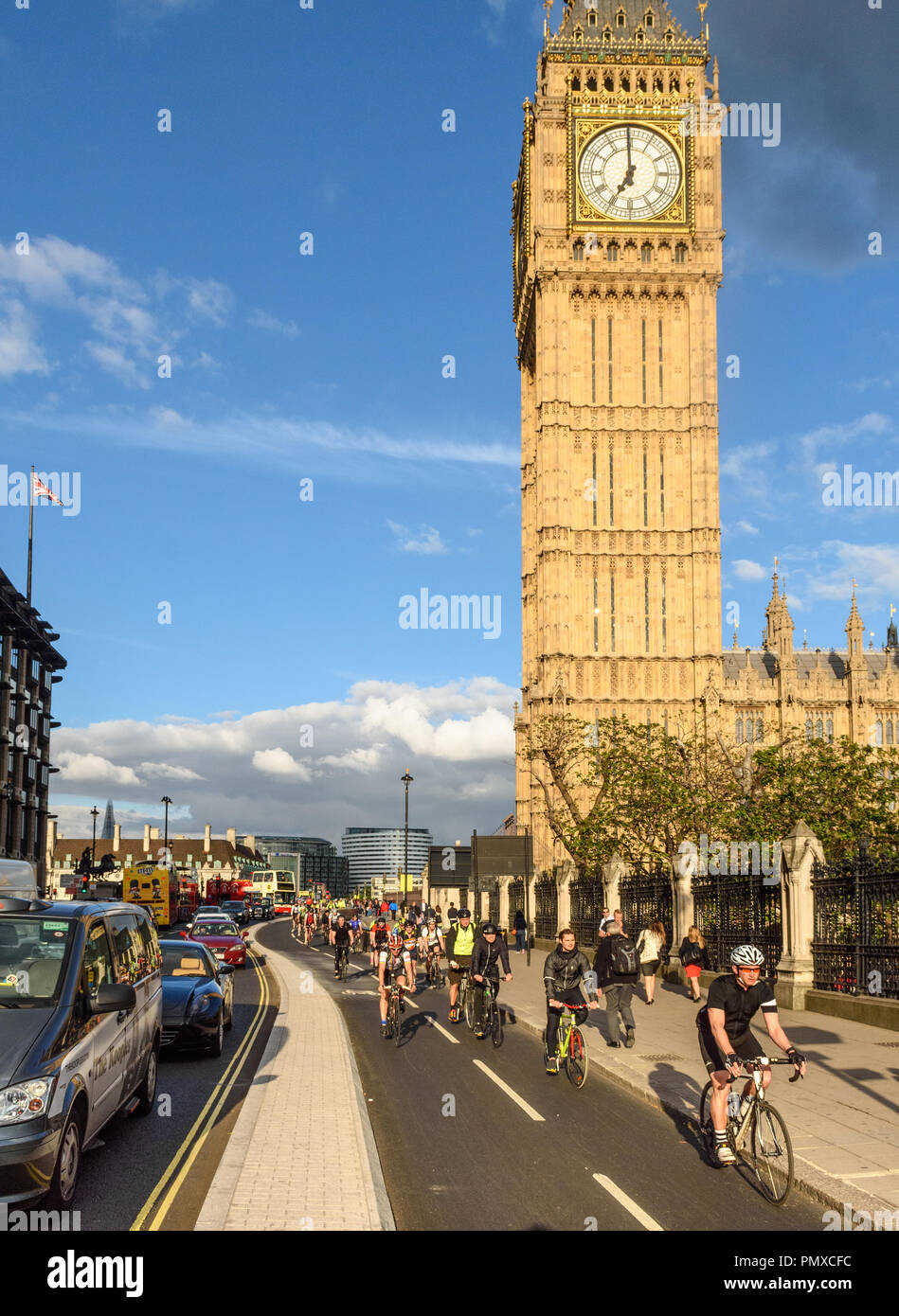 London, England - May 24, 2016: Cyclists pass the Big Ben clock tower of the Houses of Parliament on the nearly opened East-West Cycle Superhighway. Stock Photo
