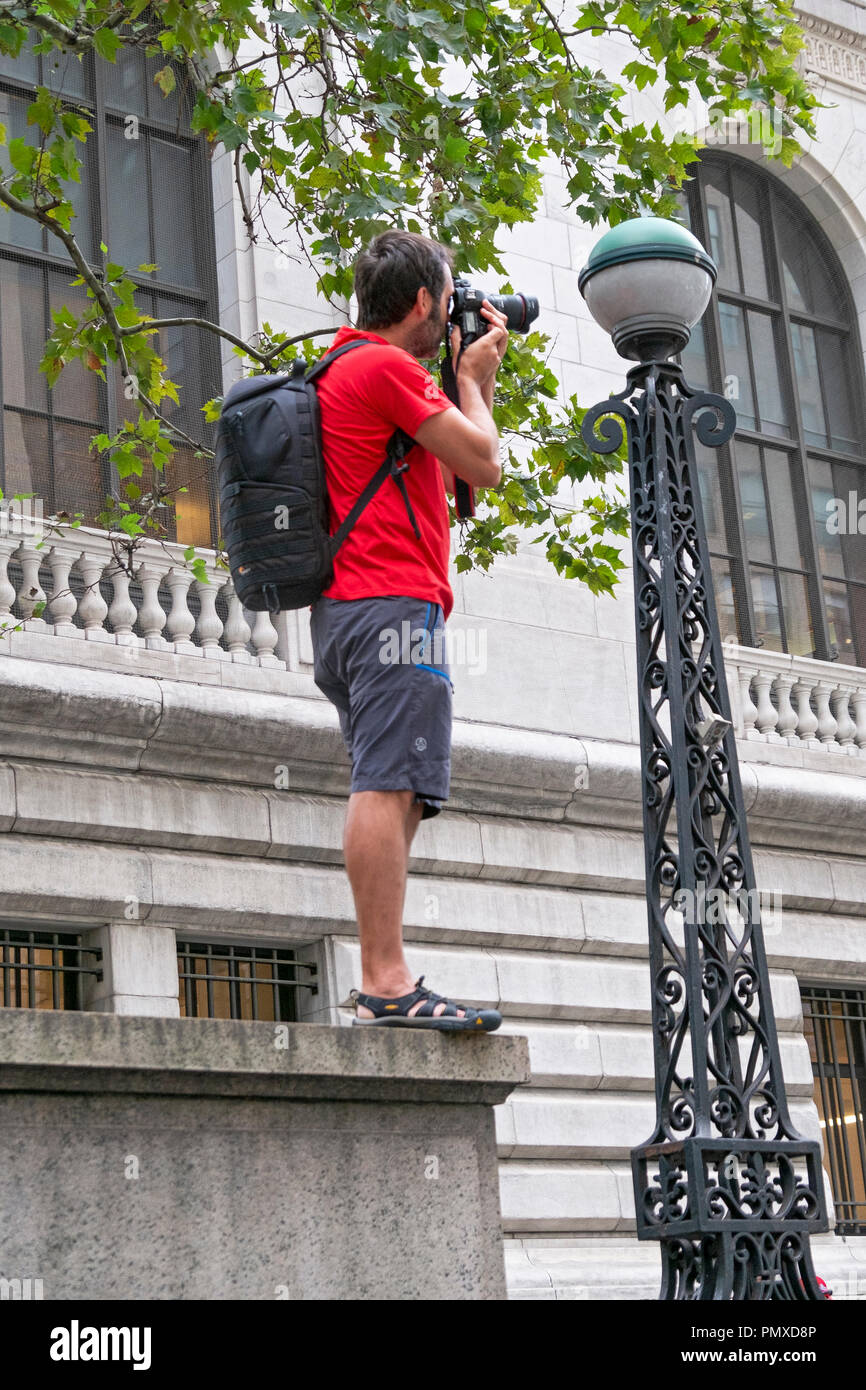A tourist in 42nd Street in Manhattan standing at the edge of ledge that's part of the exterior of the main branch of the new York Public Library. Stock Photo