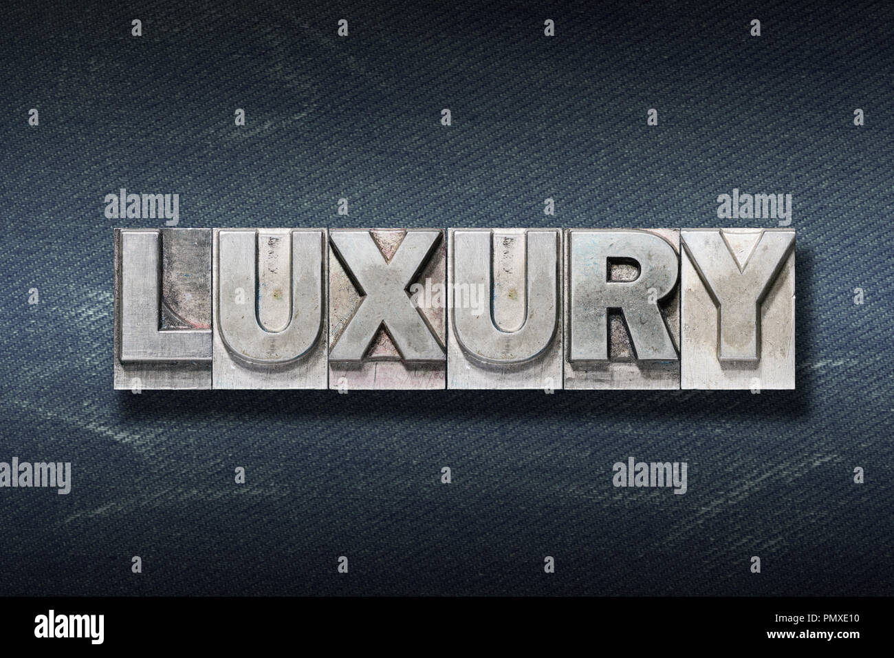 luxury word made from metallic letterpress on dark jeans background ...