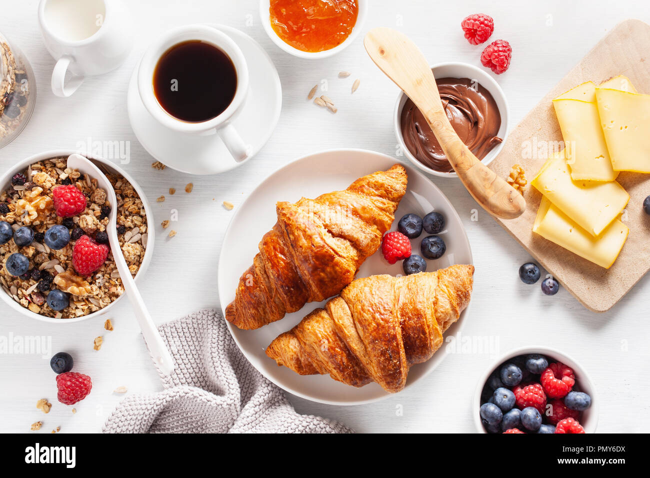 healthy breakfast with granola, berry, nuts, croissant, jam, chocolate